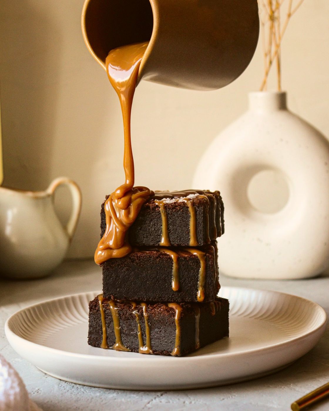 Salted brownies under a pour of caramel